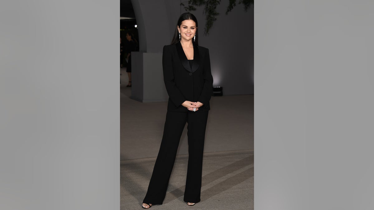 Selena Gomez poses in a black pantsuit