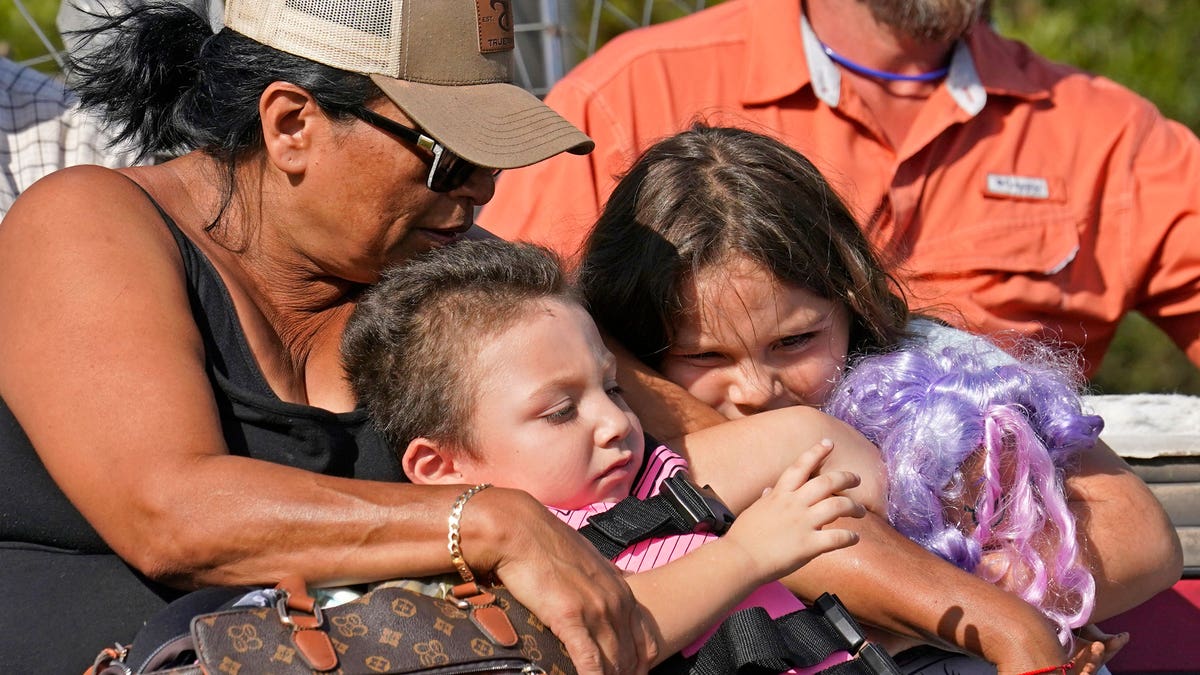 Woman holding her grandchildren as they wait to be evacuated