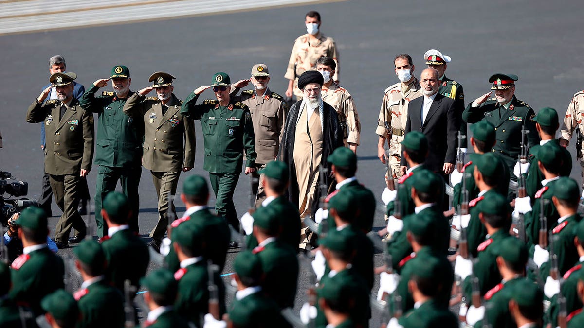 Ayatollah Khameneii walks in front of police students wearing green uniforms