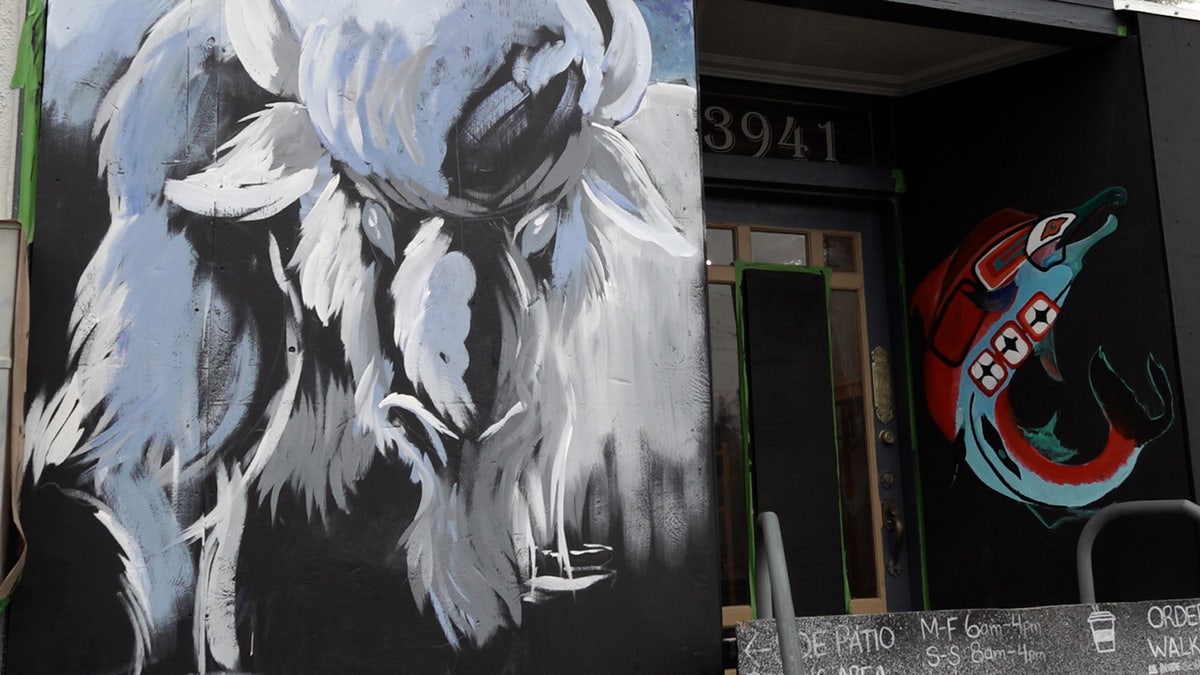 Bison and salmon painted on plywood covering Bison Coffee House windows