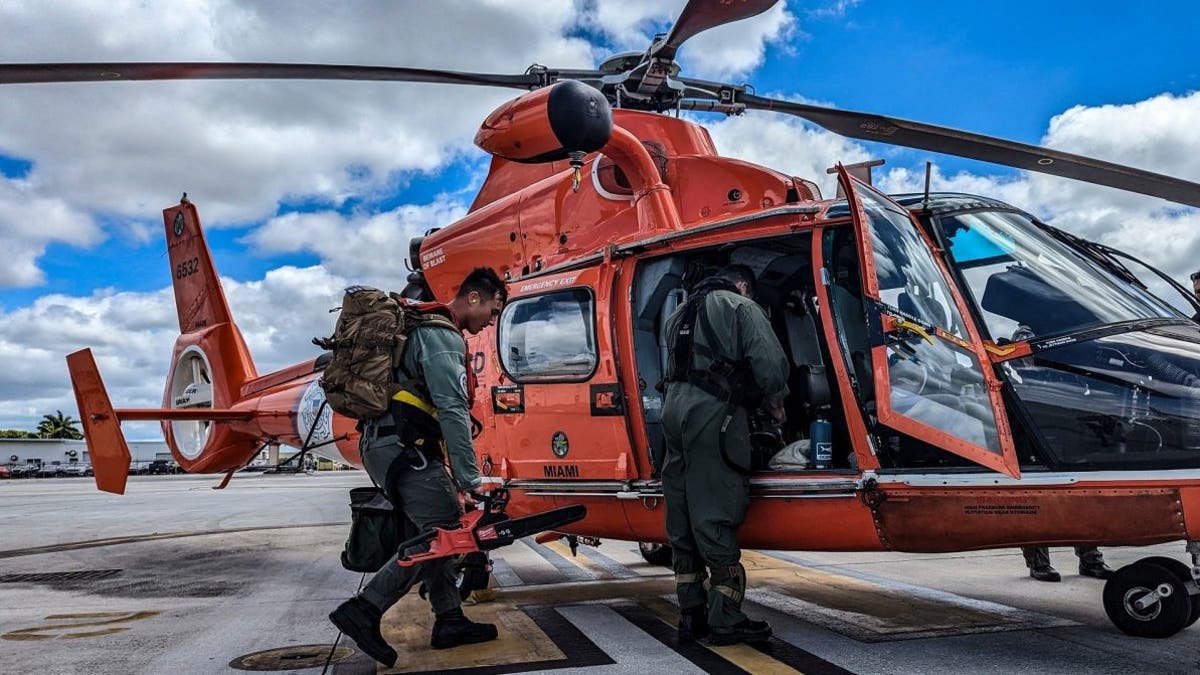 Two Coast Guard members board a helicopter