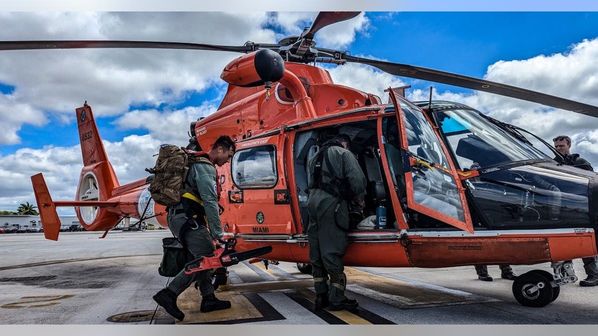 Two Coast Guard members board a helicopter