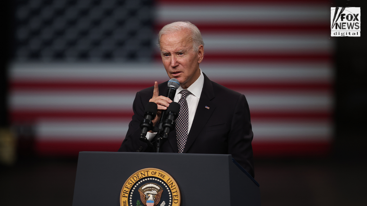President Joe Biden standing in front of an American flag and speaking at a black podium