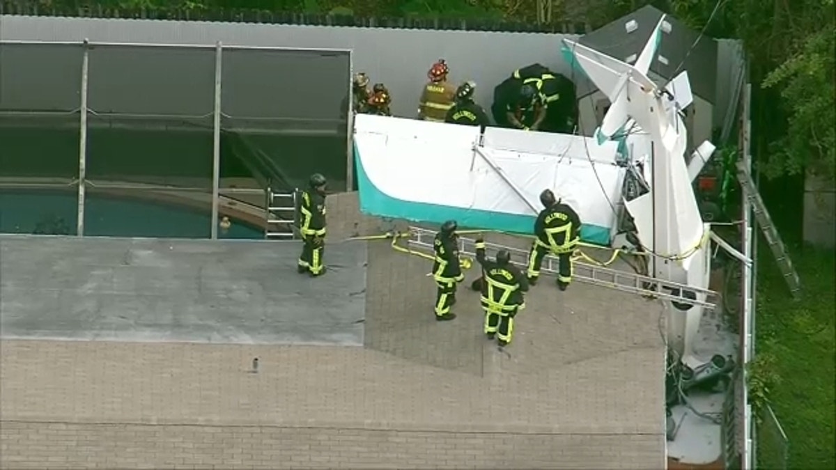 firefighters on roof by crashed plane
