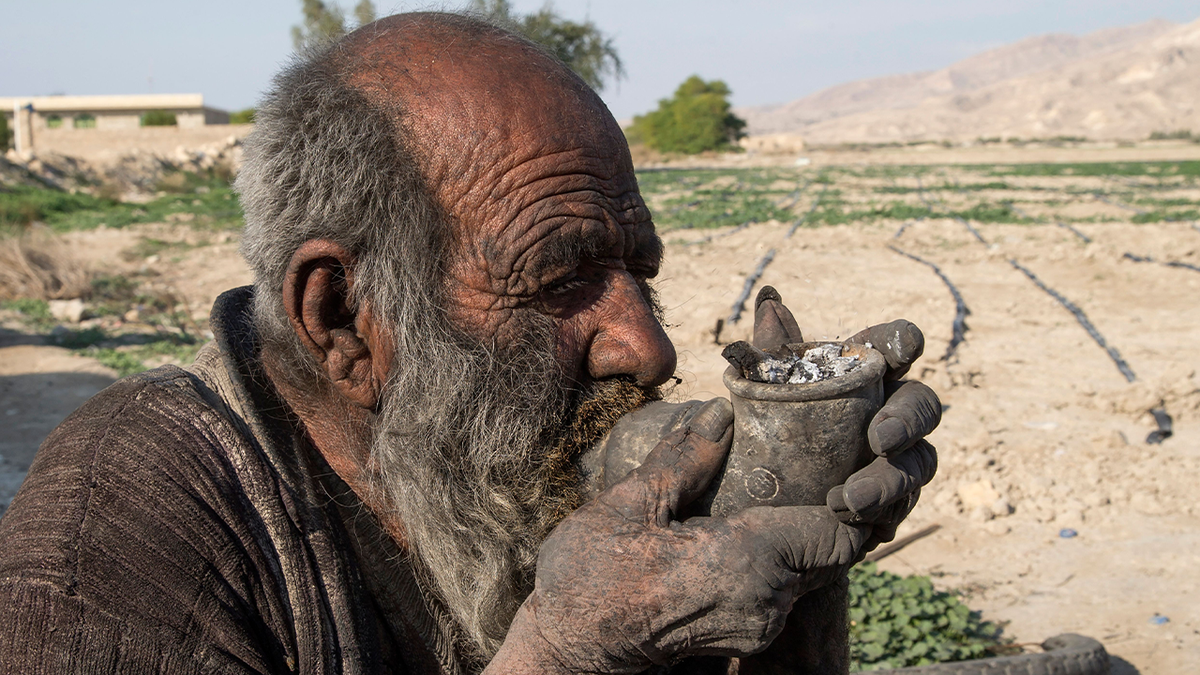 Amou Haji smokes from a pipe