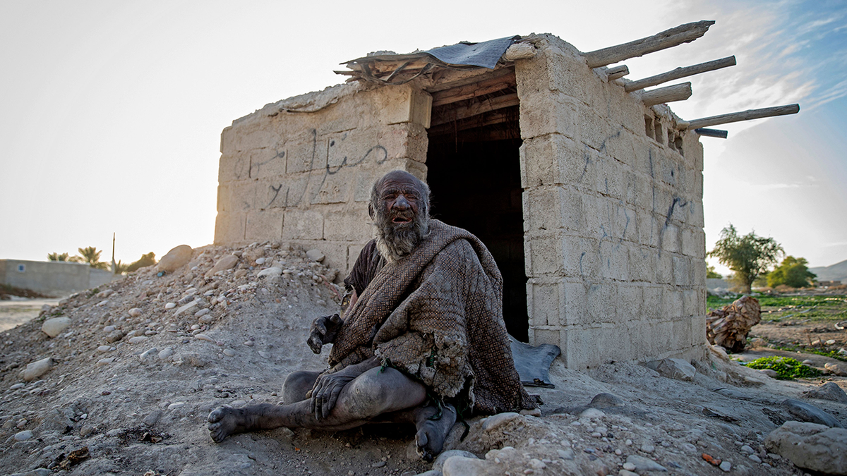 Amou Haji sits outside his cinder-block hut