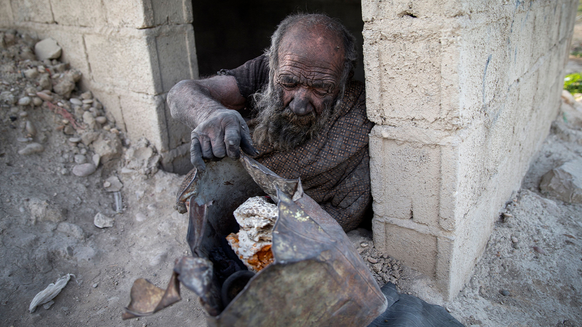 Amou Haji sits at doorstep of his cinderblock shack