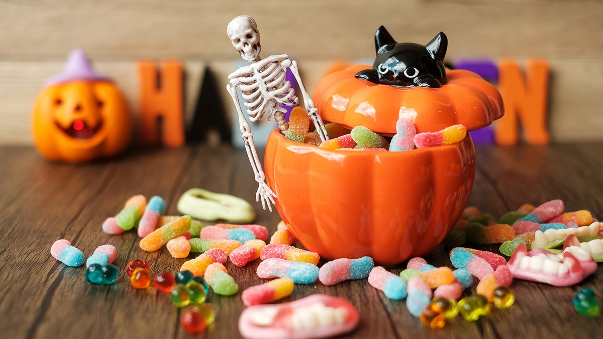 Halloween candy in ceramic pumpkin dish with decorative skeleton
