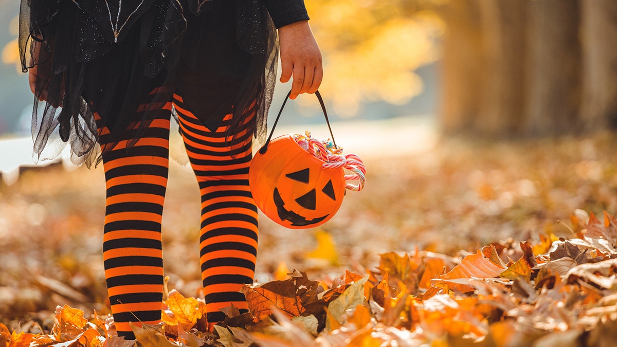 Girl holds Halloween pumpkin trick-or-treat bucket