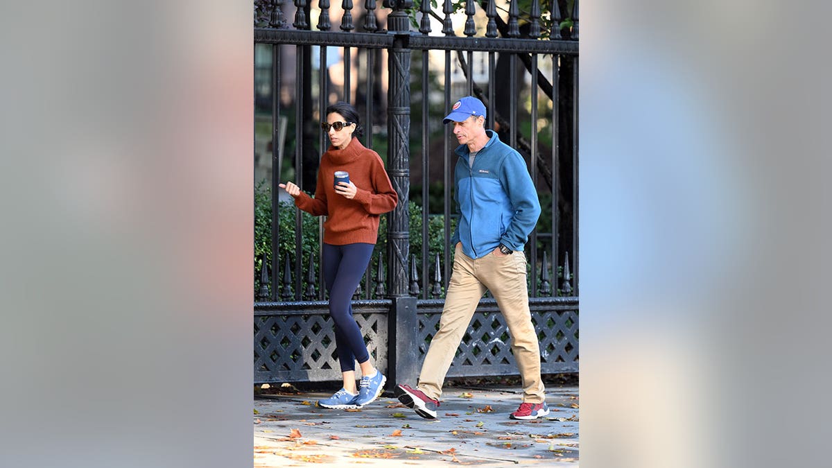 Huma Abedin wears sweater while out on a walk with her husband, wearing a blue jacket and baseball cap 