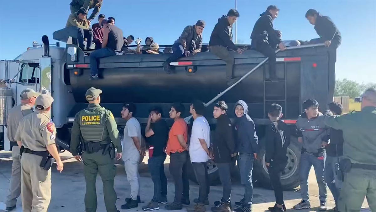 Officers walk around line of immigrants