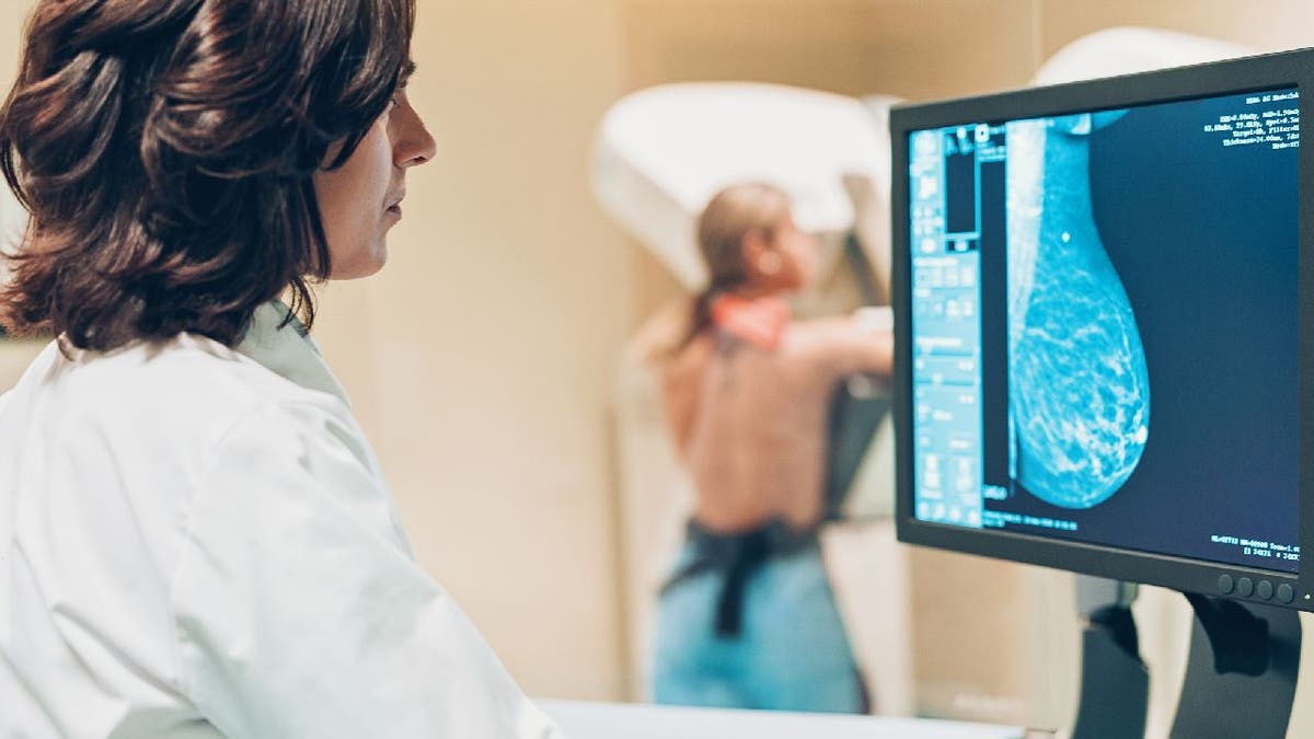 doctor looks at mammogram imagery as woman receives her screening