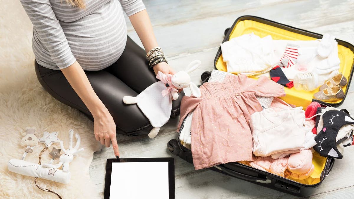 Pregnant woman packing baby clothes