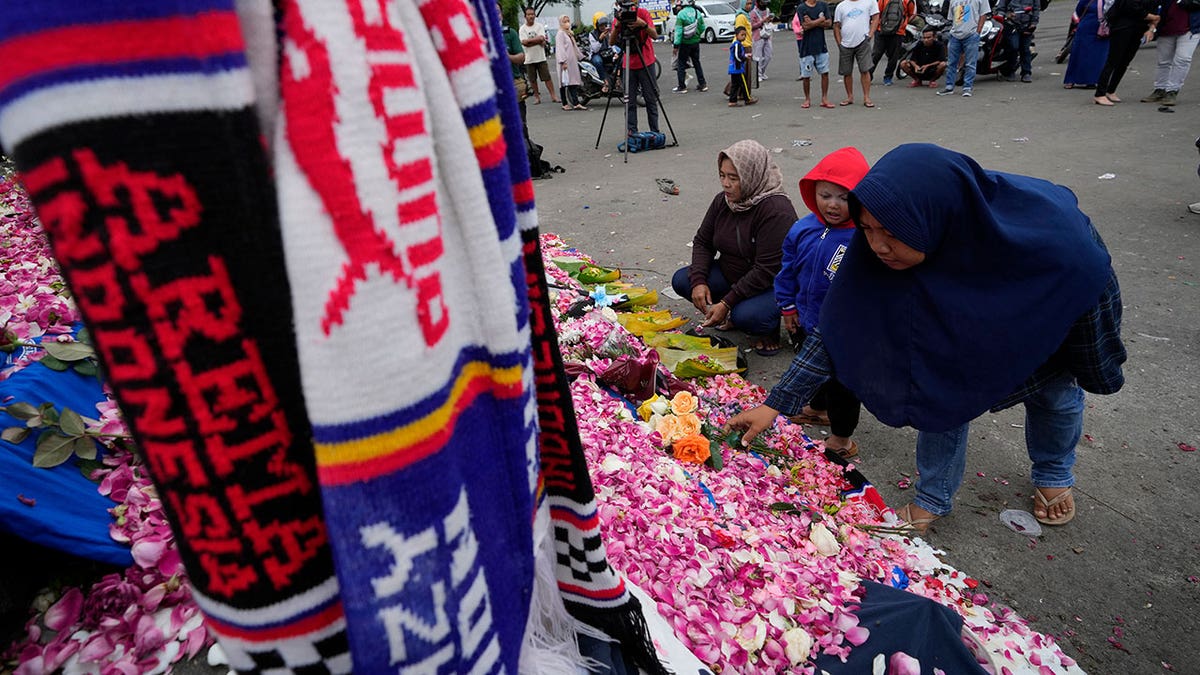 Families and mourners lay flowers outside Indonesian soccer stadium