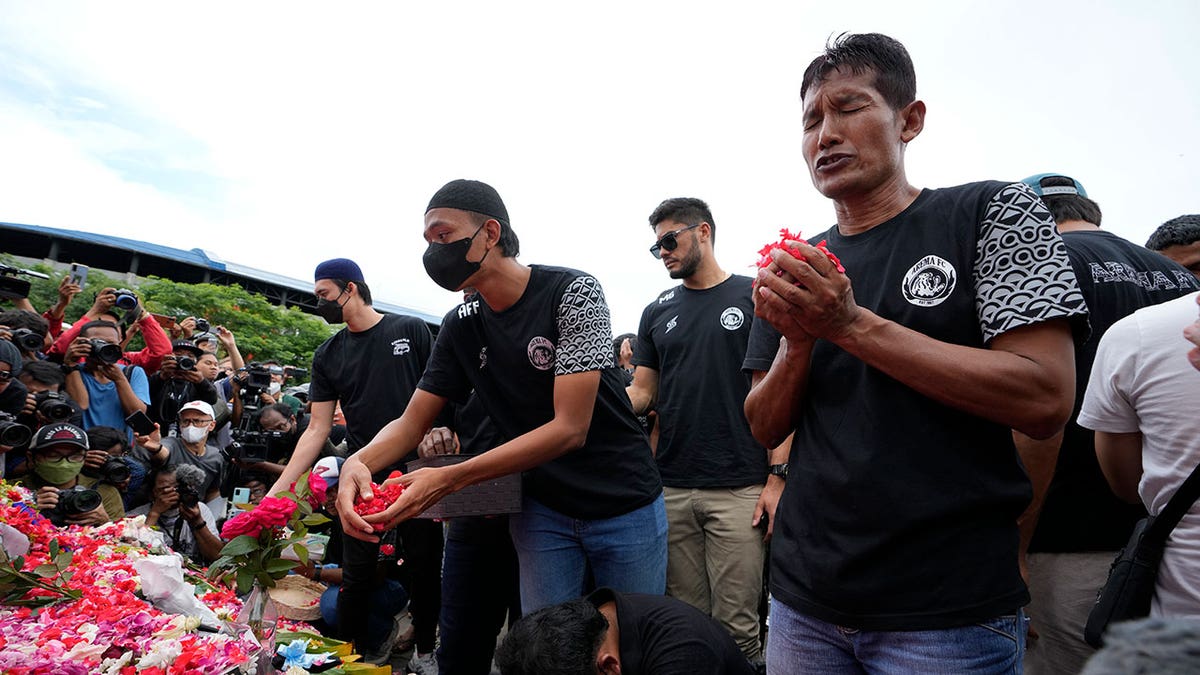Indonesian soccer players lay tributes to the victims of the soccer match stampede 