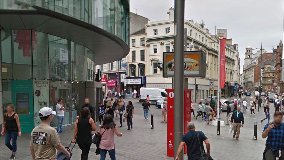 Exterior shot of Liverpool One shopping complex with stores and people walking on the street