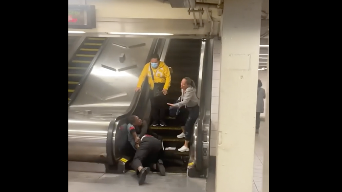 Four people at bottom of NYC escalator after fight between two people