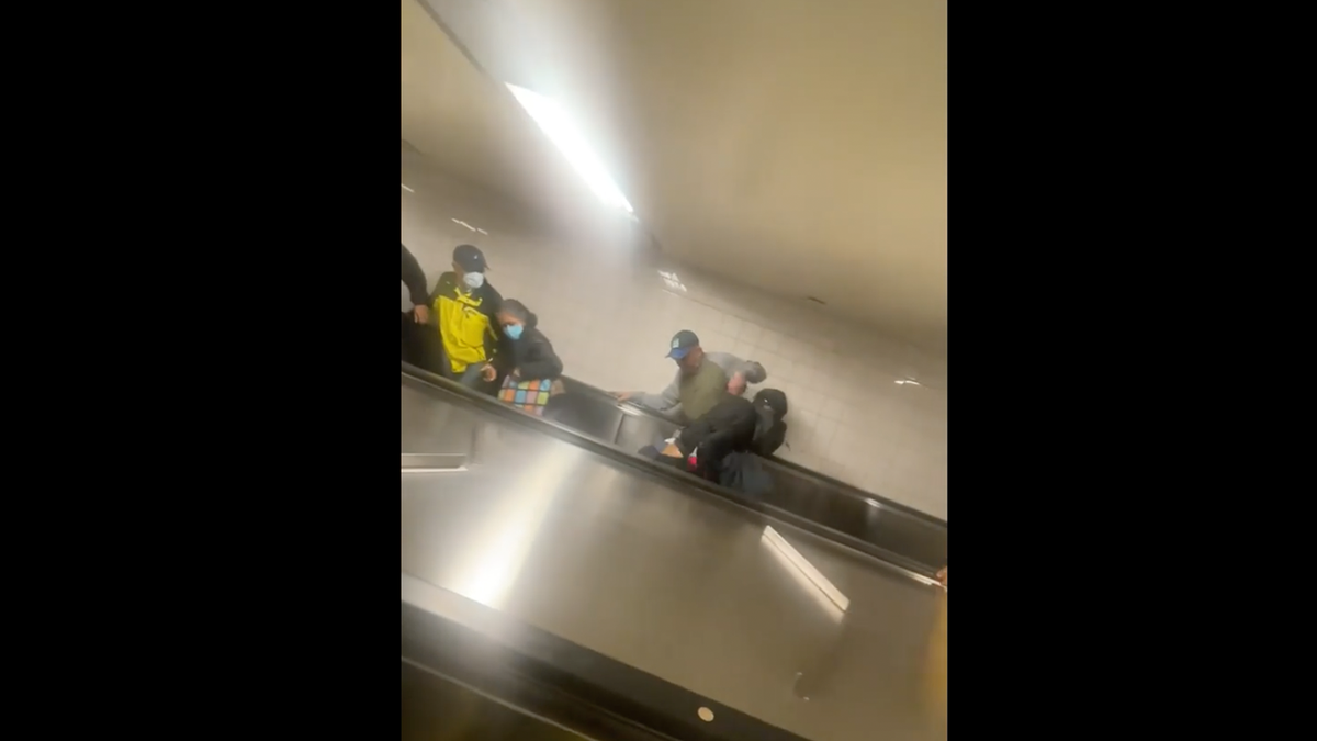 Two men fighting down escalator in NYC