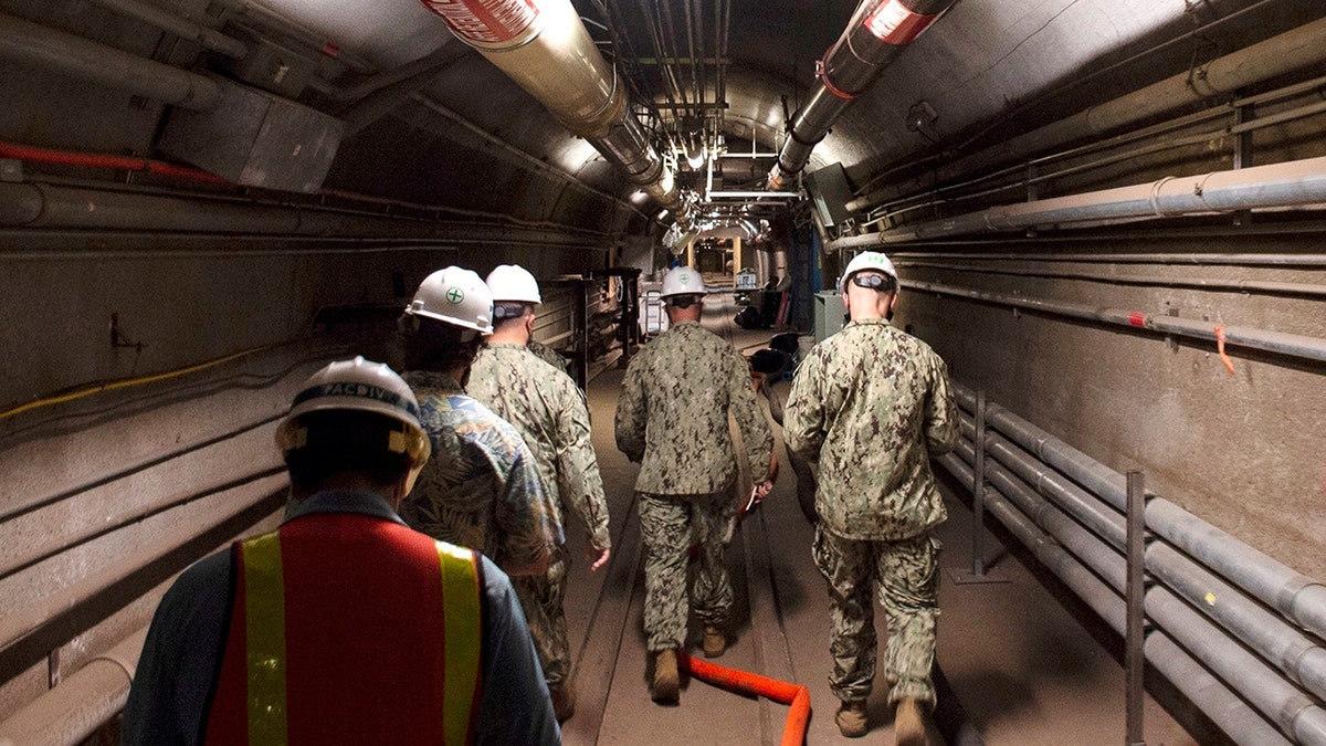 military officials walking through tunnel at facility