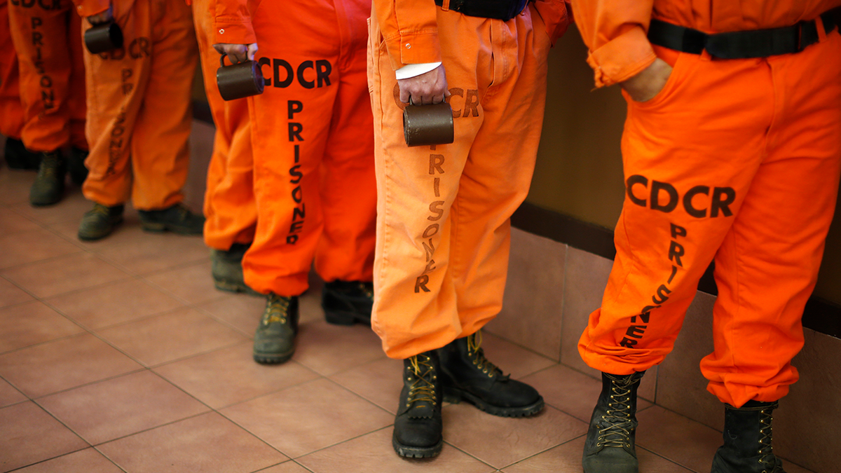 Photo shows inmates lined up while holding cups in California