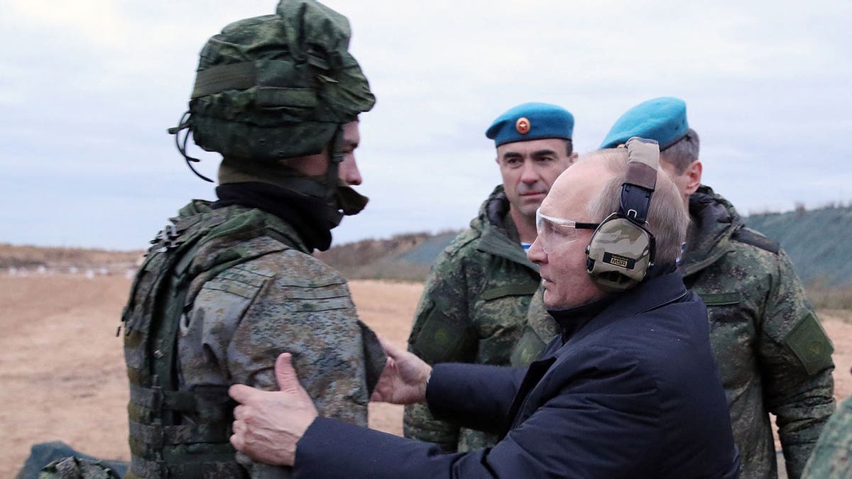 Putin wears protective ear and eye gear while speaking to soldier
