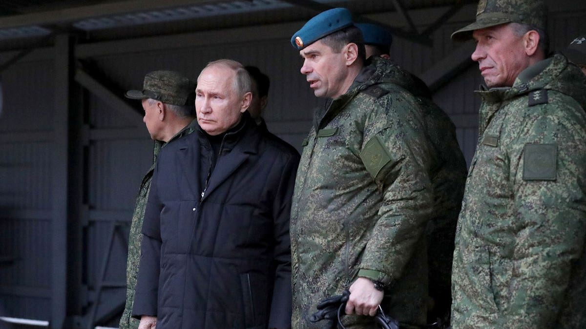 Putin stands next to soldier underneath roofed area