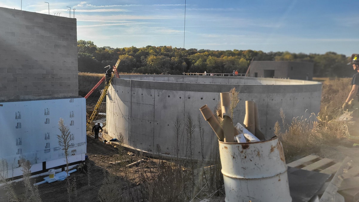 rescuers climbing into concrete tank