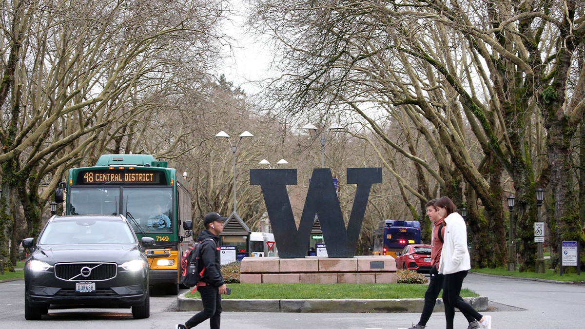 University of Washington Students walking past school's sign 