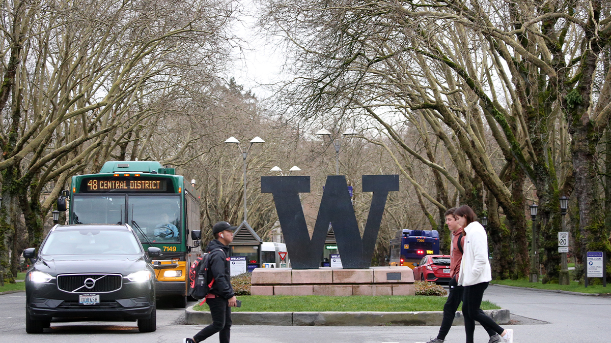 University of Washington Students walking past school's sign