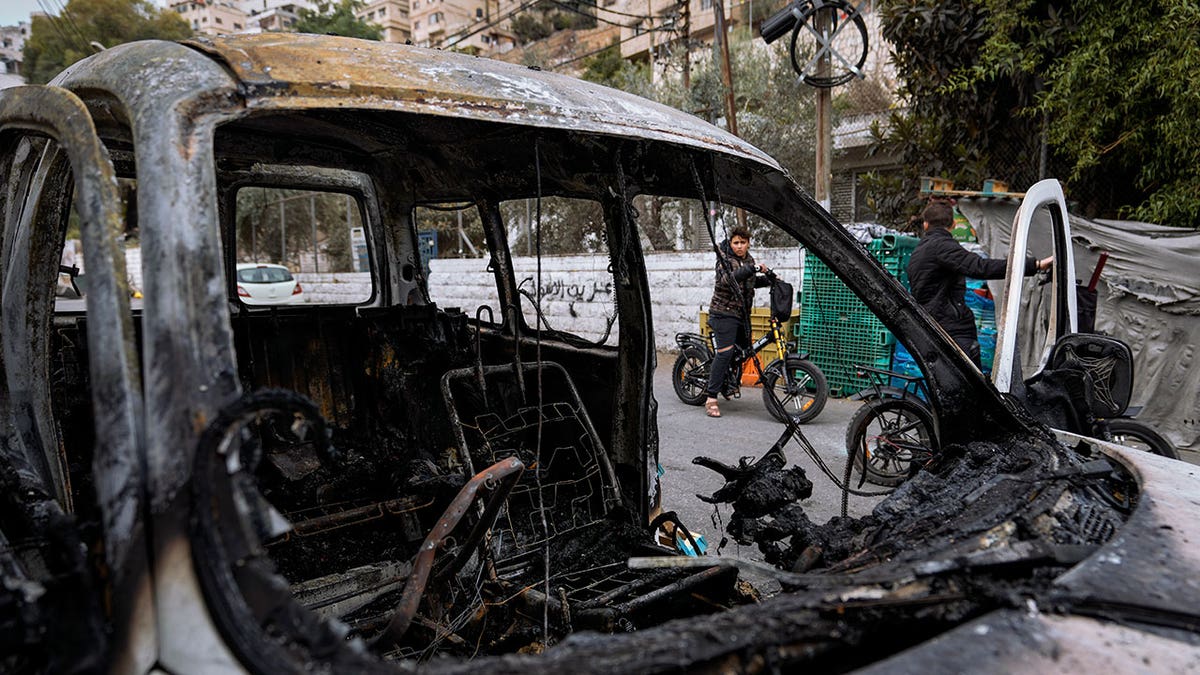 A burned car sits in the middle of a road in Israel