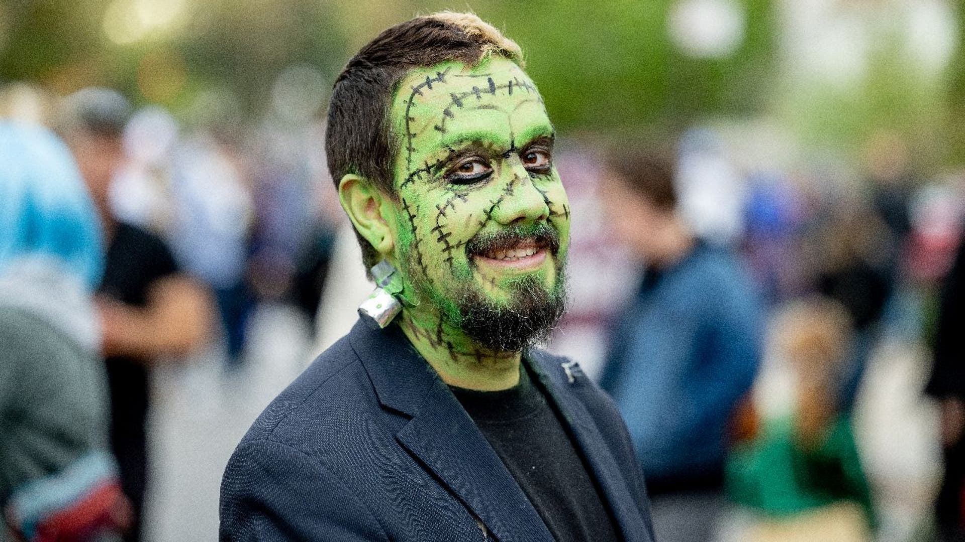 Man wears green Frankenstein face paint for Halloween