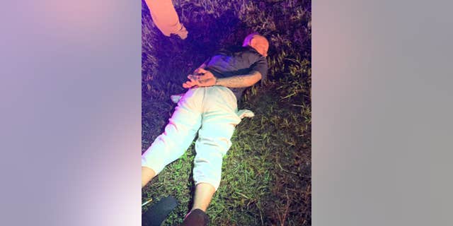 Mark Wilson lies cuffed in the grass after being arrested by the Putnam County Sheriff's Office on Aug. 27, 2020.