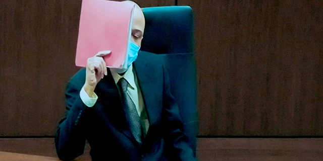 Darrell Brooks shields his face with a folder during jury selection as he appears via video from an adjacent courtroom due to his continuous interruptions Oct. 3.