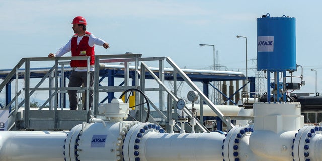 A staff member stands over a section of the Interconnector Greece-Bulgaria (IGB) gas pipeline that will transport gas from Komotini to Stara Zagora in Bulgaria, in Komotini, Greece, on July 8, 2022. 