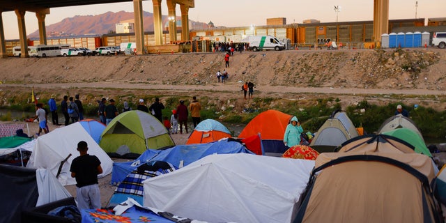 Migrantes venezolanos acampan mientras ven a otros migrantes cruzar el Río Bravo para entregarse a los oficiales de la patrulla fronteriza de EE. UU. para solicitar asilo en El Paso, Texas, Estados Unidos, en Ciudad Juárez, México, el 29 de octubre de 2022. 