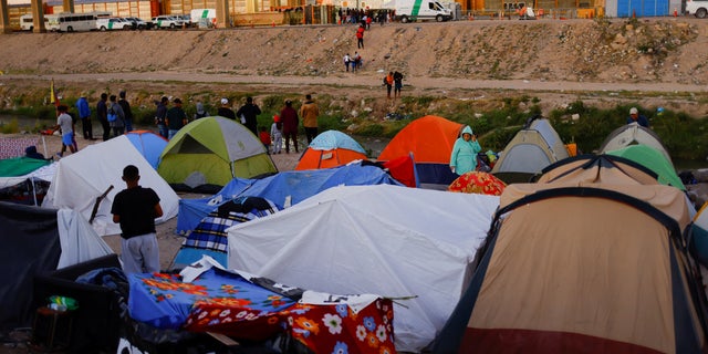 Migrantes venezolanos acampan mientras ven a otros migrantes cruzar el Río Bravo para entregarse a los oficiales de la patrulla fronteriza de EE. UU. para solicitar asilo en El Paso, Texas, Estados Unidos, en Ciudad Juárez, México, el 29 de octubre de 2022. 