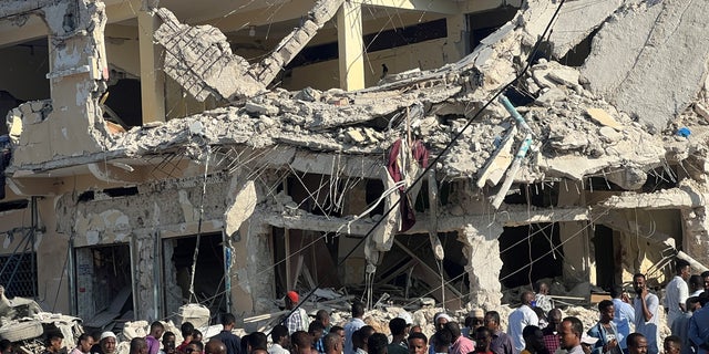 Burgers verzamelen zich bij de ruïnes van een gebouw op de plaats van een explosie langs de K5-straat in Mogadishu, Somalië op 30 oktober 2022. 