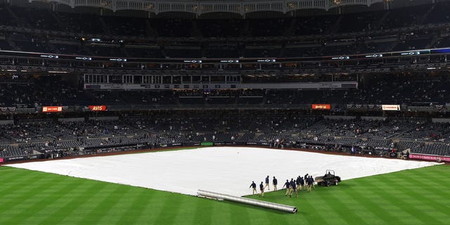 A tarp covers the infield prior to game five of the American League Division Series between the Cleveland Guardians and New York Yankees at Yankee Stadium on October 17, 2022 in New York, New York.