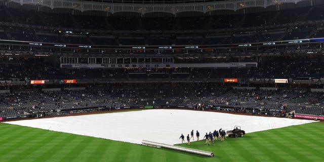 A tarp covers the infield prior to game five of the American League Division Series between the Cleveland Guardians and New York Yankees at Yankee Stadium on October 17, 2022 in New York, New York.