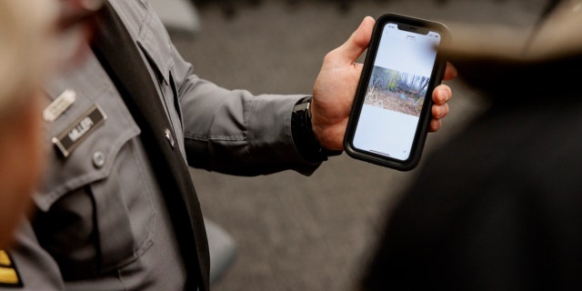 Cpl. Brent Miller shows a photograph of the location where remains of the young woman, previously known only as Jane "Newport" Doe, were discovered Nov. 17, 2012.