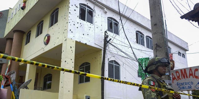 <strong>A Mexican Army member stands guard in front of the bullet-ridden building of the Municipality of San Miguel Totolapan in Guerrero, Mexico, in October 2022.</strong>