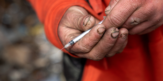 Man in Seattle holding a needle for meth use