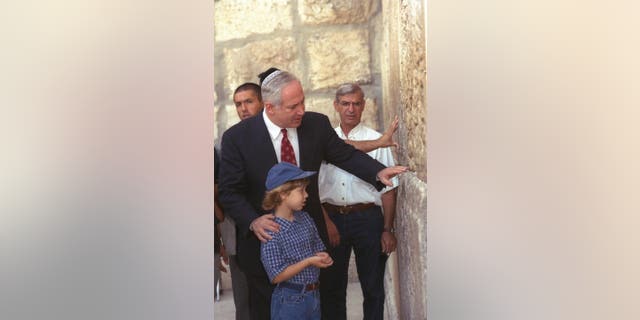 Prime Minister Benjamin Netanyahu places a written wish at the Western Wall with his son, Yair, in Jerusalem circa 1998.