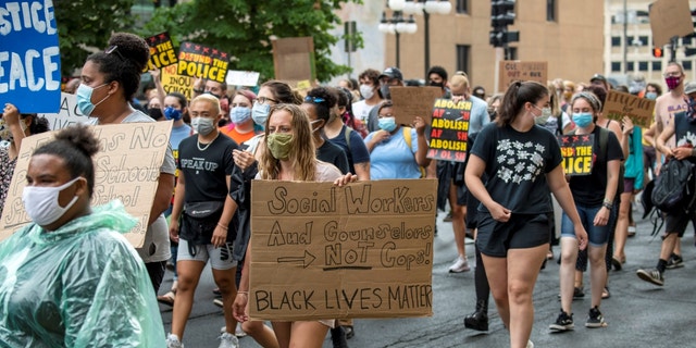 Protester marching with a "social workers and counselors, not cops" sign in August 2020, months after the death of George Floyd.
