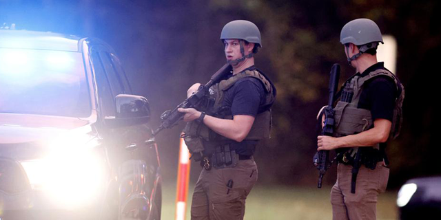 Law enforcement stand at the entrance to Neuse River Greenway Trail parking at Abington Lane following a shooting in Raleigh, N.C., Thursday, Oct. 13, 2022.