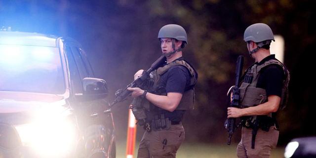 Law enforcement stand at the entrance to Neuse River Greenway Trail parking at Abington Lane following a shooting in Raleigh, North Carolina, Thursday, Oct. 13, 2022.