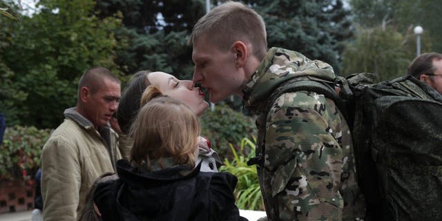 A Russian recruit and his wife kiss outside a military recruitment center in Volzhskiy, Volgograd region, Russia, Wednesday, Sept. 28, 2022. Russian President Vladimir Putin has ordered a partial mobilization of reservists to beef up his forces in Ukraine. 