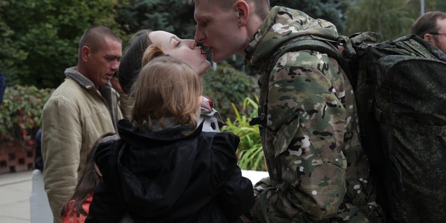 A Russian recruit and his wife kiss outside a military recruitment center in Volzhskiy, Volgograd region, Russia, Wednesday, Sept. 28, 2022. Russian President Vladimir Putin has ordered a partial mobilization of reservists to beef up his forces in Ukraine. 