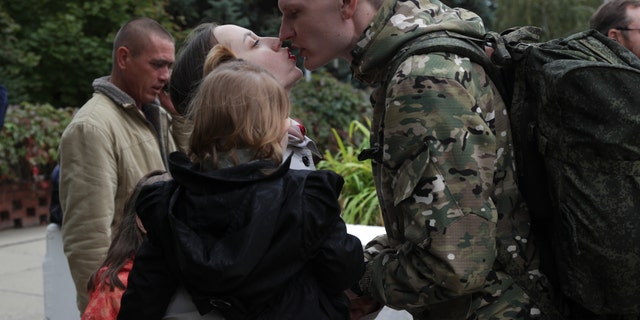 A Russian recruit and his wife kiss outside a military recruitment center in Volzhskiy, Volgograd region, Russia, Wednesday, Sept. 28, 2022. Russian President Vladimir Putin has ordered a partial mobilization of reservists to beef up his forces in Ukraine. 