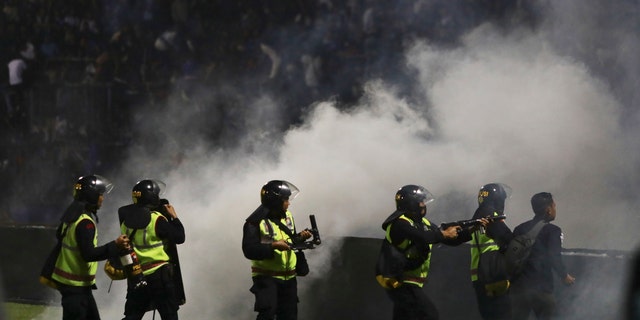 Police officers fire tear gas during a soccer match at Kanjuruhan Stadium in Malang, East Java, Indonesia, Saturday, Oct. 1, 2022.